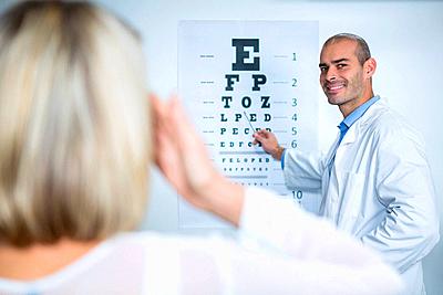 Male optometrist taking eye test of female patient-stock-photo