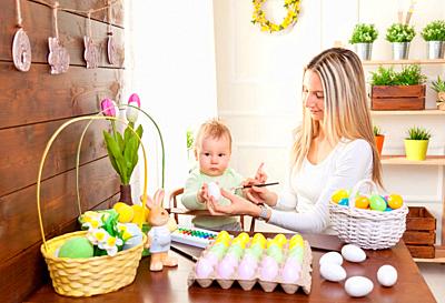 Easter concept. Happy mother and her cute child getting ready for Easter by painting the eggs-stock-photo