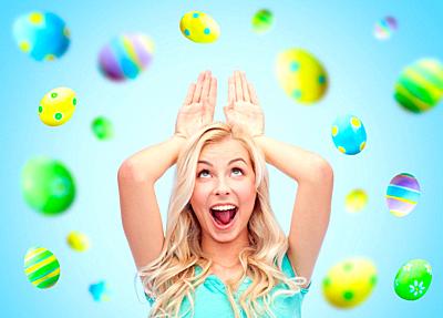 happy woman making bunny ears over easter eggs-stock-photo