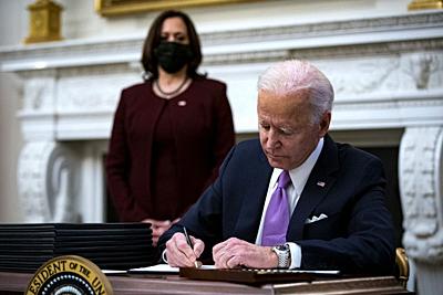 U.S. President Joe Biden signs an executive order after speaking during an event on his administration's Covid-19 response with U.S. Vice President Kamala Harris, left, in the State Dining Room of the White House in Washington, D.C., U.S., on Thursday, Jan. 21, 2021. Biden in his first full day in office plans to issue a sweeping set of executive orders to tackle the raging Covid-19 pandemic that will rapidly reverse or refashion many of his predecessor's most heavily criticized policies. .Credit: Al Drago / Pool via CNP | usage worldwide. - Washington/District of Columbia/United States of America-stock-photo
