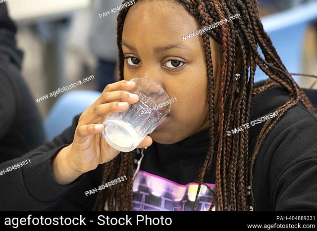 Schoolgirl having breakfast, drinking milk with volunteers from the project in the kitchen, the Brotzeit project is intended to enable children to start the...