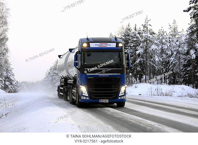 Salo, Finland - December 23, 2018: Volvo FH bulk transport truck up front driving on snowy road in arctic conditions, with high beam lights on briefly