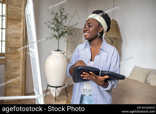 Leisure. Contented african woman in light clothes near the mirror