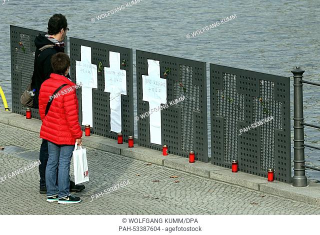 Tourists look at the places where crosses devoted to victims of the Berlin Wall, now replaced with paper crosses, next to the Reichstag Building along the Spree...