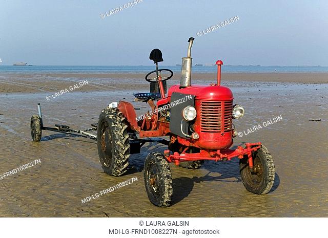 Old tractor on the beach to bring boats back at low tide