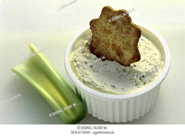 A Bowl of Herbed Dip with a Cracker and Celery Stick