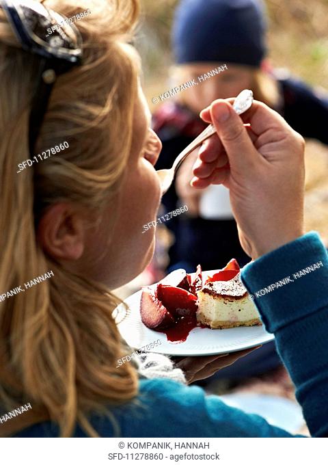 A woman enjoying a cheesecake with plum compote