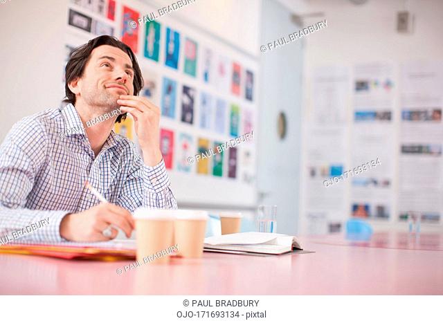 Businessman looking up with surrounded by coffee cups in office