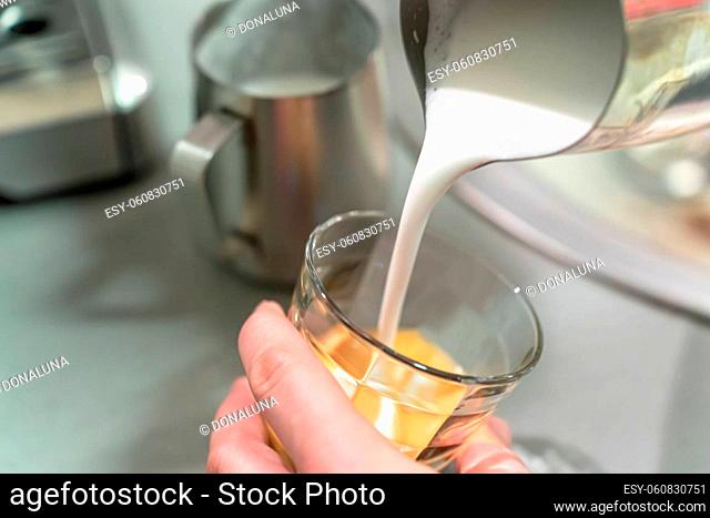 Barista pours milk foam into an espresso glass