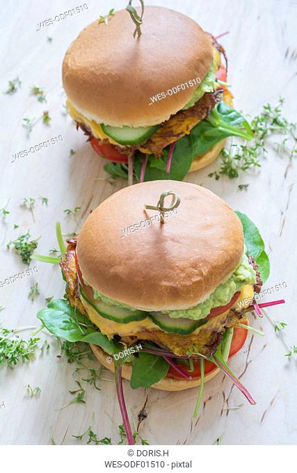 Two veggie burgers with sweet potato patties, avocado dip, cheese and vegetables