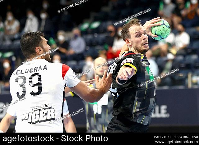 11 July 2021, Bavaria, Nuremberg: Handball: International match, Germany - Egypt in the Arena Nürnberger Versicherung. Kai Häfner (r) from Germany fights his...