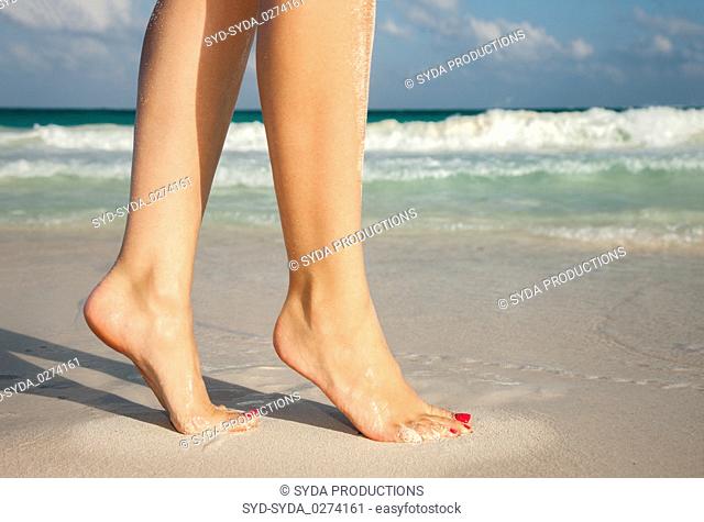 closeup of woman legs walking on beach sand