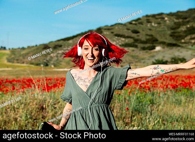 Red-haired woman dancing on poppy field