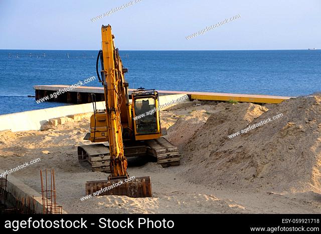 Excavator at sea straightens the sand for the beach