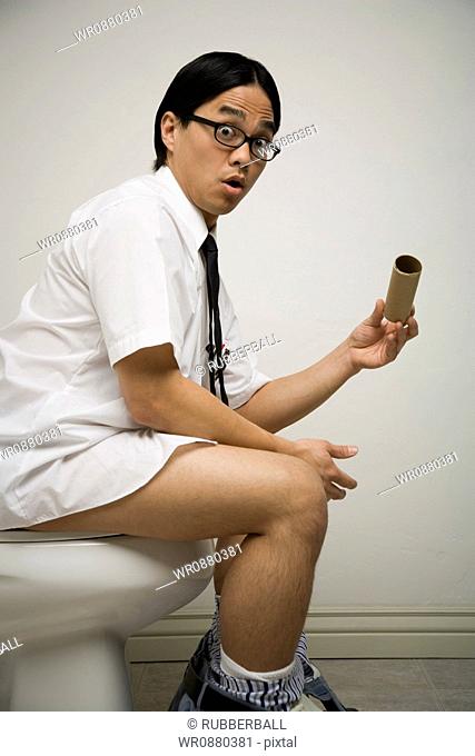 Portrait of a young man sitting on a toilet