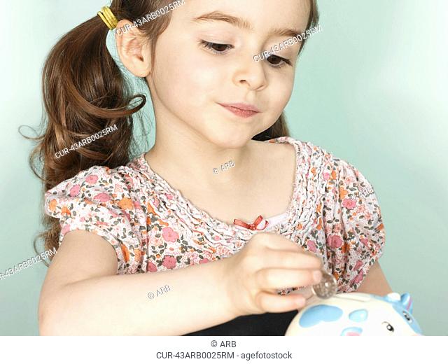 Girl putting coins in piggy bank