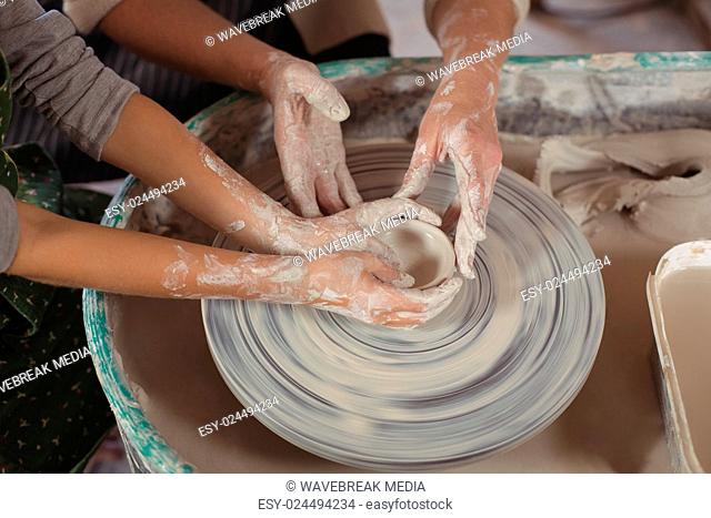 Mid section of female potter assisting girls