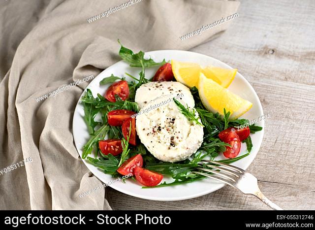 Mozzarella salad with arugula, cherry tomatoes, lemon, seasoned with spices and olive oil
