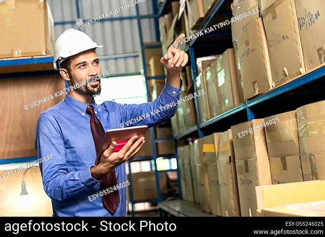 White caucasian middle east warehouse manager hold digital tablet to do inventory in warehouse distribution center environment