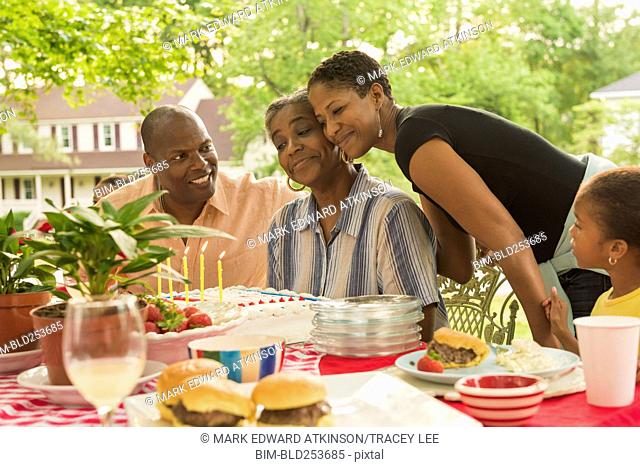 Multi-generation family celebrating with cake at picnic