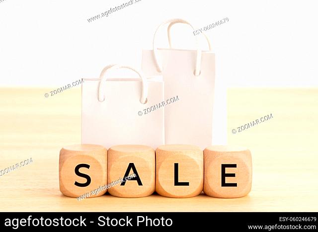 Sale concept. Word on wooden blocks and blank paper shopping bags on table. White background