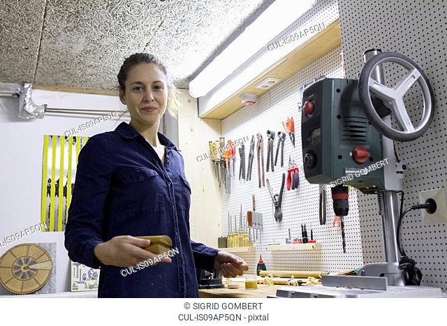 Portrait of young female carpenter at workbench in workshop