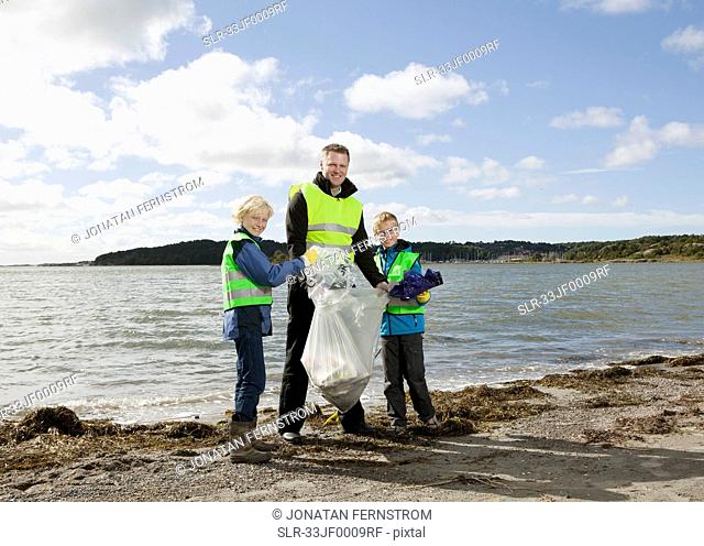 Father and sons cleaning beach