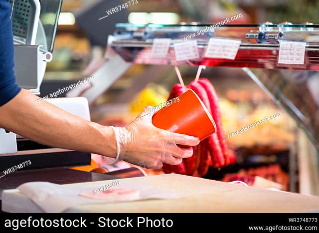 Woman in butcher shop holding sausage in her hands to sell them