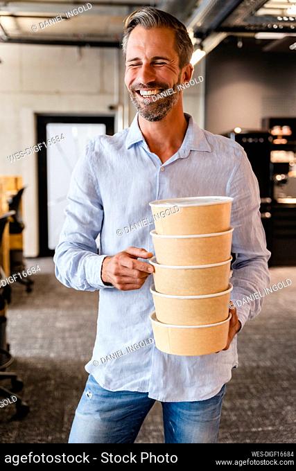 Businessman holding stack of lunch boxes in office