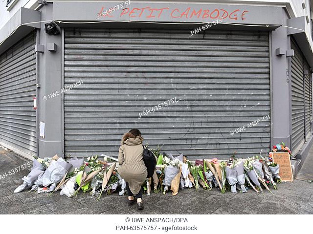 A woman lays flowers outside the Le Petit Cambodge bar in Rue Alibert in Paris, France, 14 November 2015. At least 120 people have been killed in a series of...