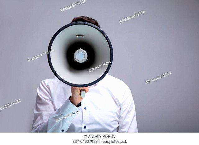 Man Doing Announcement Using Megaphone Against Gray Background