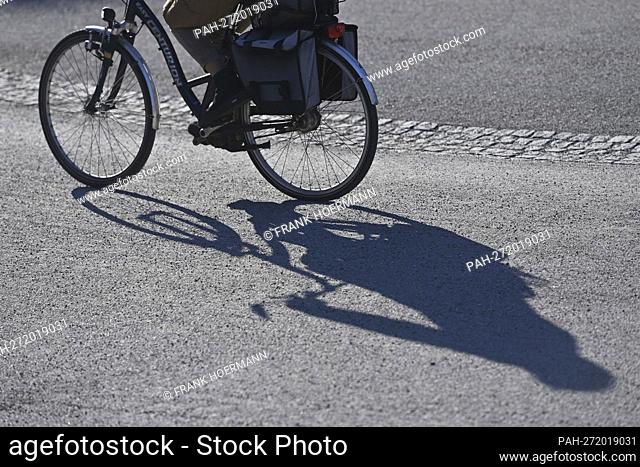 Cyclist, cyclist, woman, cyclist rides a bike through Munich and casts a long shadow. - Munich/Bayern/Deutschland