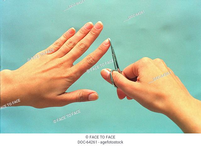 right hand cuts the fingernails of the left hand with nail-scissors