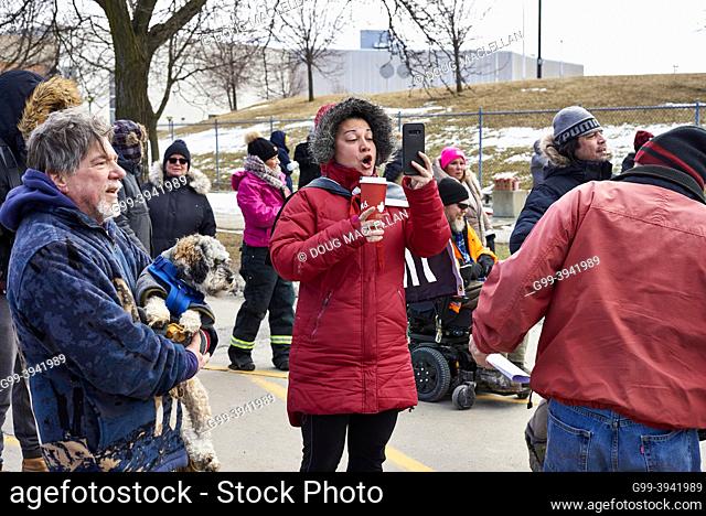 A woman protester makes a live feed on social media at a police barrier on 12 February 2022 near the Freddom Convoy blockade of the Ambassador Bridge in Windsor