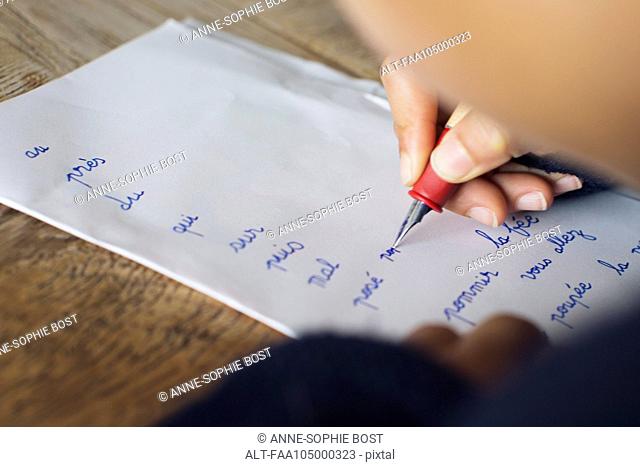Child writing in cursive on paper, cropped