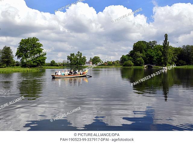 21 May 2019, Saxony-Anhalt, Oranienbaum-Wörlitz: A gondola with tourists drives along the world-famous Wörlitzer Park in front of the Palm House