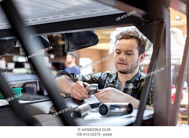 Focused mechanic examining car part in auto repair shop
