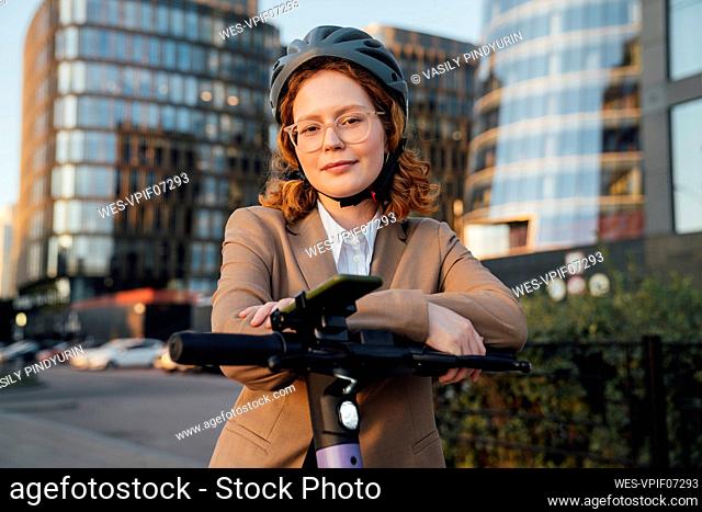 Beautiful businesswoman with eyeglasses leaning on push scooter