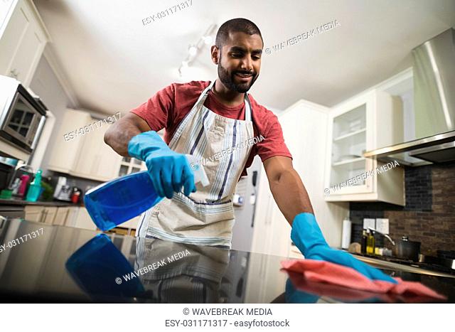 Low angle view of man cleaning marble counter in kitchen
