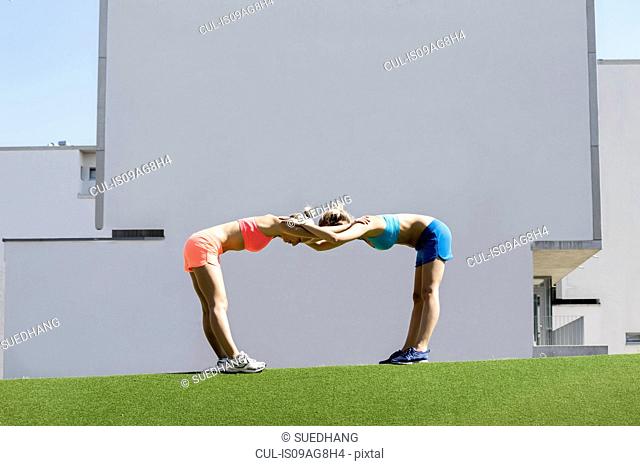 Two young female athletes exercising together in park