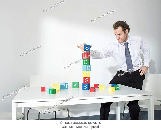 Business man playing with blocks