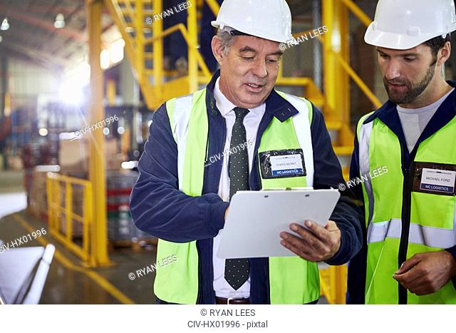 Manager and worker with clipboard meeting in distribution warehouse