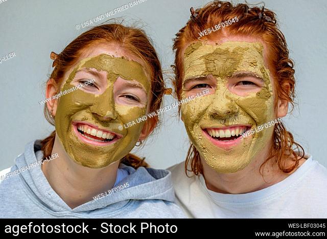 Portrait of laughing brother and sister with facial masks