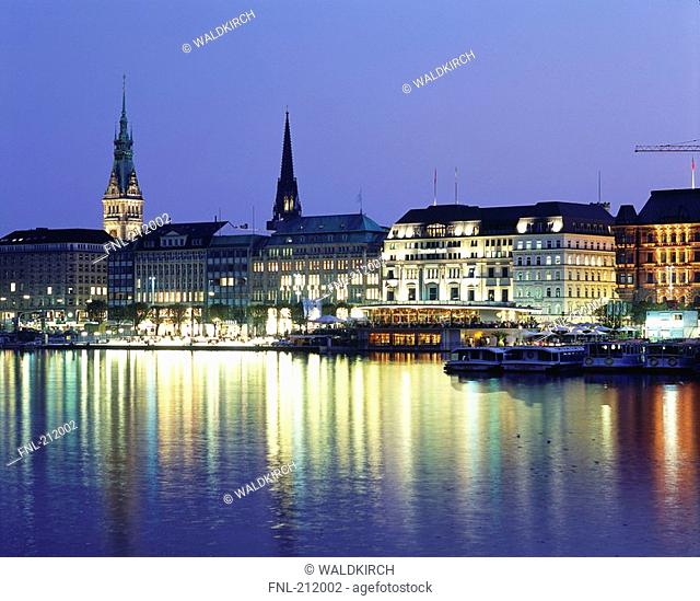 Boats in river with lit up buildings in background, River Alster, Hamburg, Germany