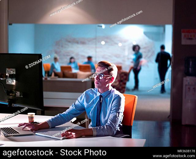 Young man working on computer at night in dark office. The designer works in the later time