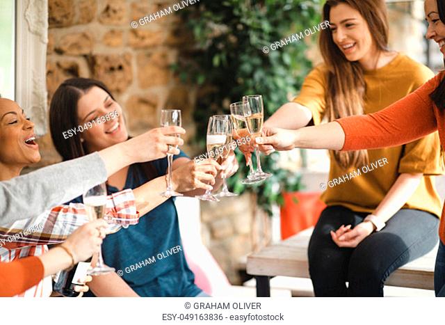 Small group of female friends celebrating with a glass of champagne. They're making a celebratory toast