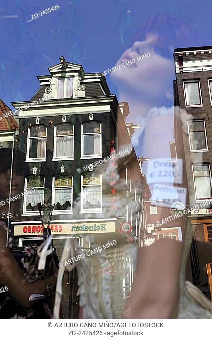 A mannequin in a shop window with reflection of a building. Amsterdam, The Netherlands