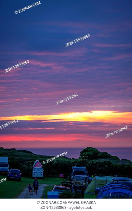 St. Ives, England - May 2018 : Cars, tents and people on a camping site at dusk on the Cornish coast, Cornwall, UK