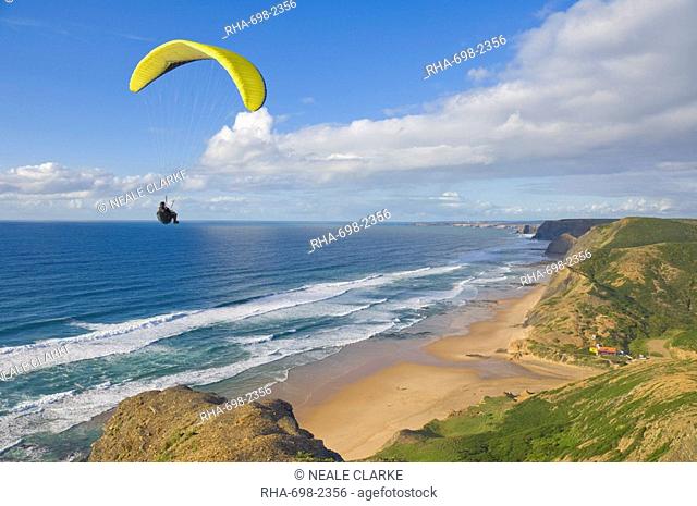 Paraglider with yellow wing above the south west coast of Portugal, Costa Vincentina, Praia do Castelejo and Cordama beaches near Vila do Bispo, Algarve