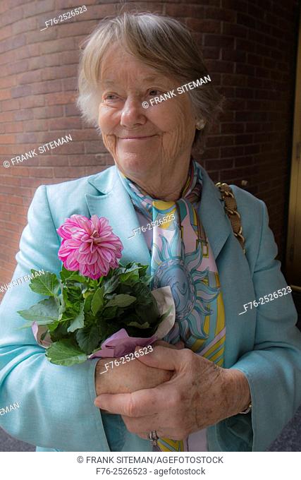 Portrait of elder woman wearing silk scarf and holding a bouquet of cut flowers